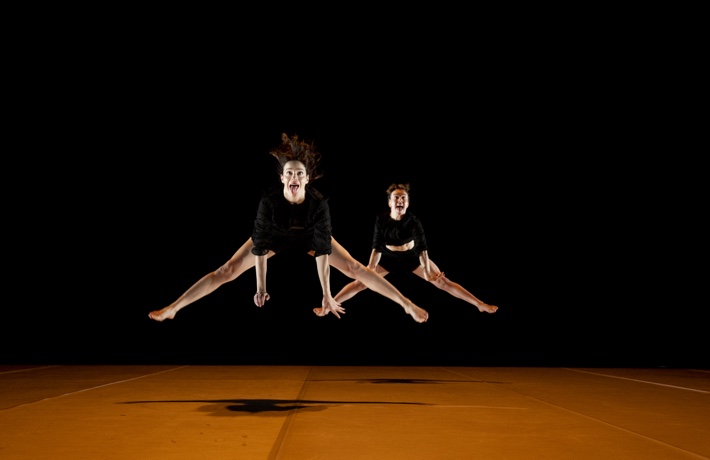Deux membres de la Oups dance company sautent en l’air en tirant la langue, avec les jambes tendues.