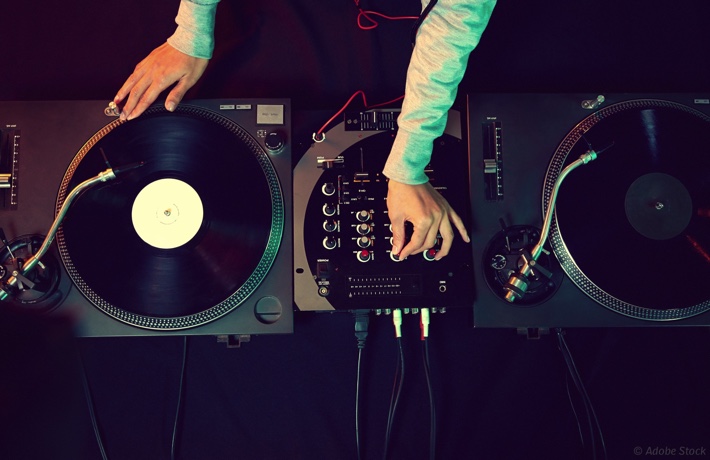 DJ manipulant un table de mixage branchée à deux platines vinyles.