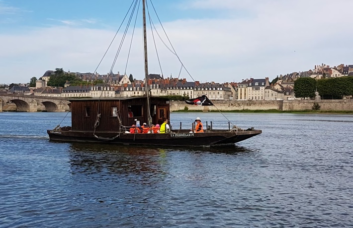 Fûtreau avec passagères et passagers équipés d’une bouée, sur la Loire, près du pont Jacques-Gabriel.
