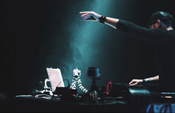 DJ Controle Z en train de mixer sur ses platines, une main en l'air en direction du public hors cadre.