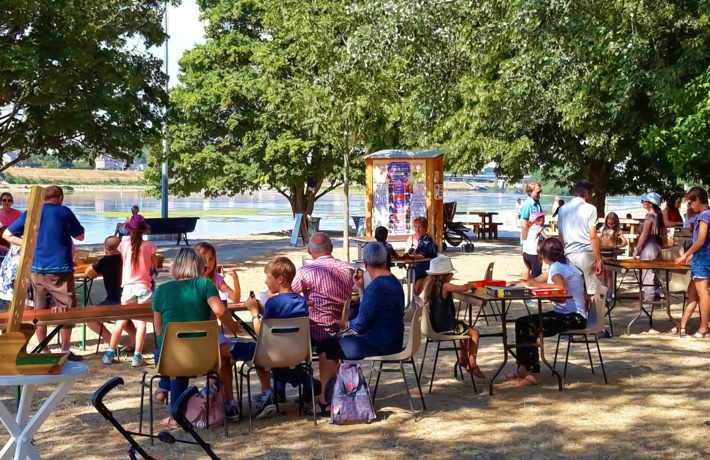 Quelques dizaines de personnes jouent à des jeux de société en petits groupes, attablés sur les rives du port de la Creusille.