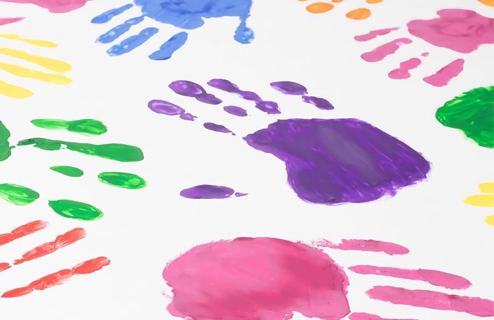 Empreintes de main peintes de différentes couleurs sur du papier blanc.
