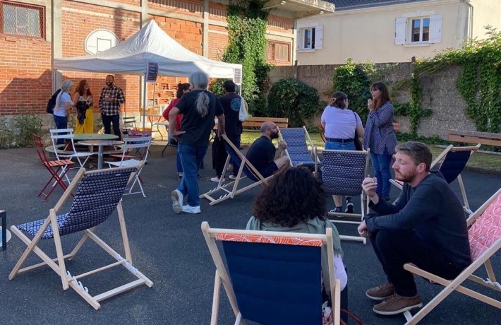 Des petits groupes de personnes échangent dans la cour de l’ALCV, en partie dans des chaises longues.