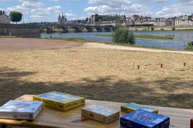 Des jeux de société posés sur une table dans le port de la Creusille, avec la Loire en arrière-plan.