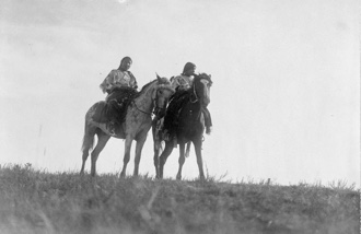 Photo noir et blanc d’époque : deux personnes autochtones à cheval.