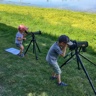 Deux jeunes enfants au bord de l’eau utilisent un téléscope.