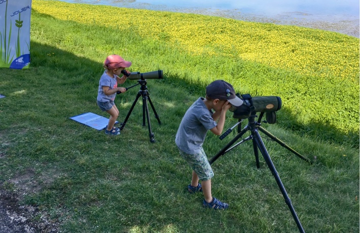 Deux jeunes enfants au bord de l’eau utilisent un téléscope.