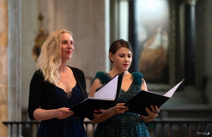 Deux chanteuses tenant leur livret au milieu d’une église.