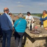 Des personnes en haut d’une tour du château écoutent une guide-conférencière présenter le patrimoine, avec des verres d’apéritifs à leurs côtés.