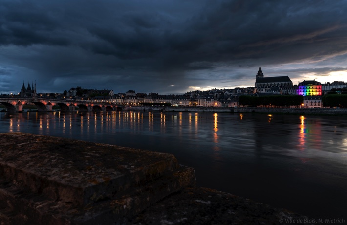 L’Hôtel de Ville photographié depuis la rive gauche, illuminé des couleurs de l’arc-en-ciel à droite, et le pont Jacques-Gabriel à gauche.